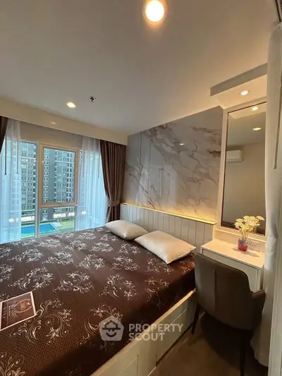 Modern bedroom with elegant decor and city view, featuring a cozy bed and stylish vanity area.