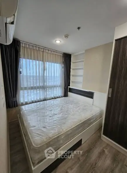 Modern bedroom with large window and built-in storage in a stylish apartment.