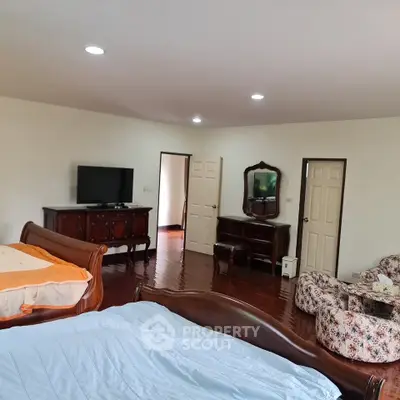 Spacious bedroom with elegant wooden furniture and cozy seating area.