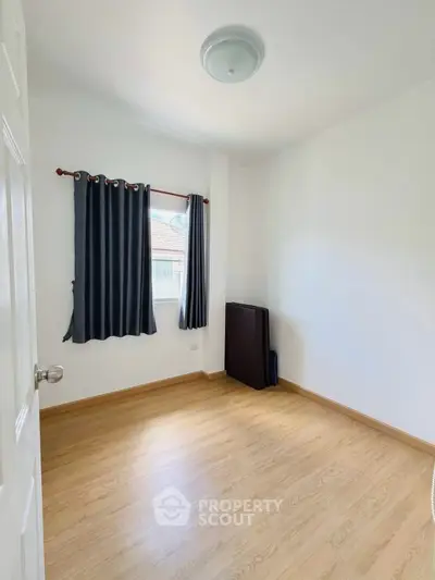 Bright and airy small room with wooden flooring and window view, perfect for a cozy study or guest room.
