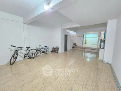 Spacious interior with bicycles, tiled floor, and staircase leading to upper level.