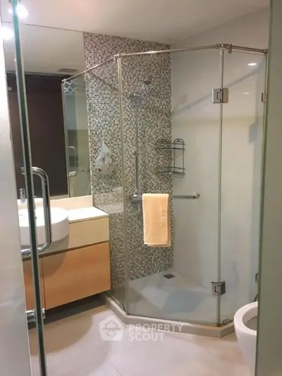 Modern bathroom with glass shower enclosure and stylish vanity in a contemporary apartment.