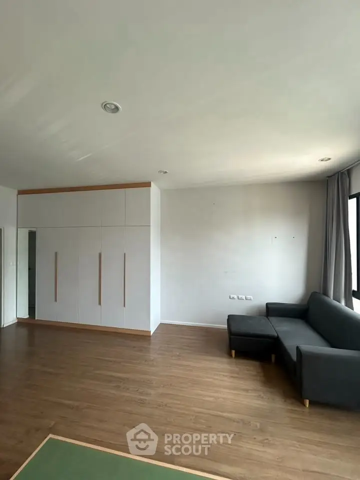 Spacious living room with modern sofa and built-in wardrobe, featuring elegant wooden flooring.