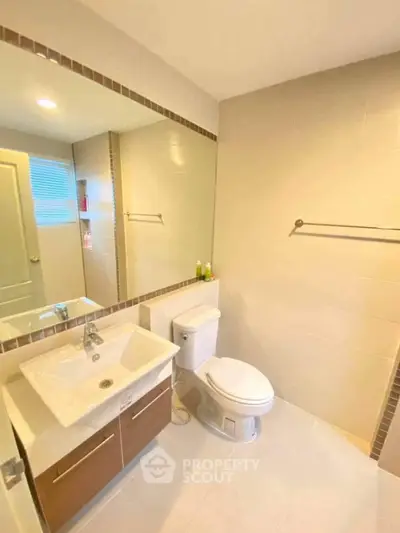 Modern bathroom with sleek fixtures and large mirror in a bright setting.