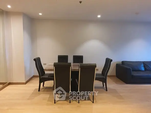 Spacious dining area with elegant black chairs and a cozy sofa, perfect for modern living.