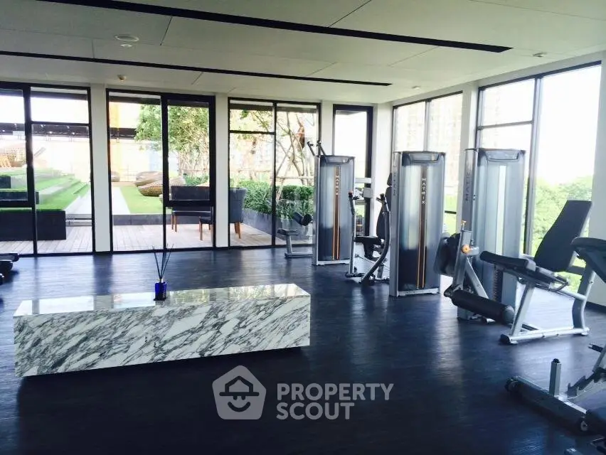 Luxurious gym with modern equipment and garden view in upscale residential building.