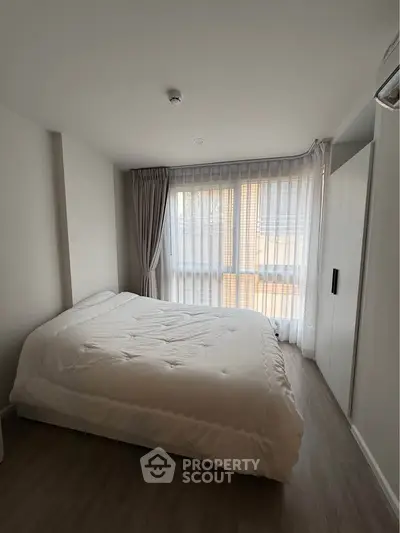 Spacious bedroom with large window and modern decor in a stylish apartment.