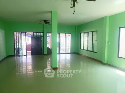 Spacious living room with green walls and large windows for natural light.