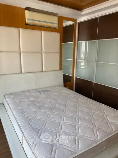 Modern bedroom with stylish headboard and built-in wardrobe, featuring a comfortable mattress and wooden flooring.