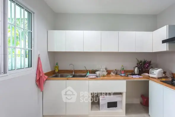 Modern kitchen with white cabinets and wooden countertops, featuring a microwave and appliances.