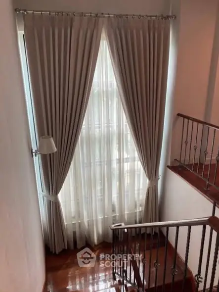 Elegant staircase with floor-to-ceiling window and luxurious drapes