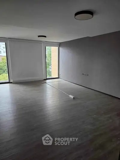 Spacious empty room with large windows and modern flooring, ideal for customization.