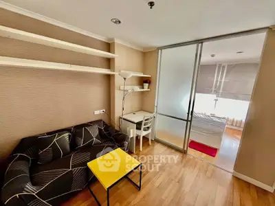 Modern studio apartment with cozy living area and sliding glass partition to bedroom.