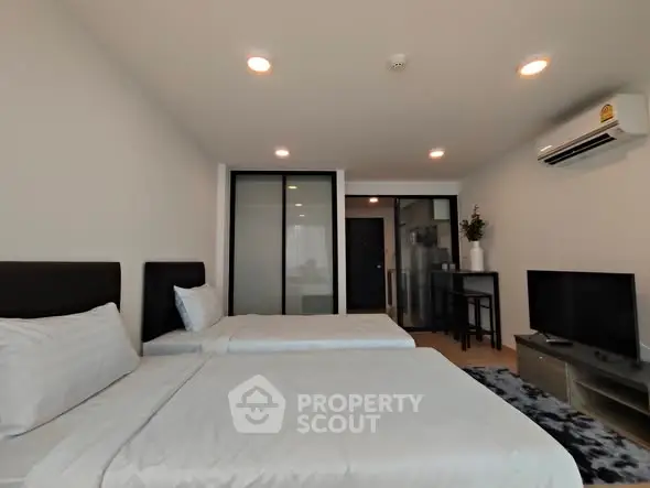 Modern bedroom with two beds, air conditioning, and TV in a stylish apartment.