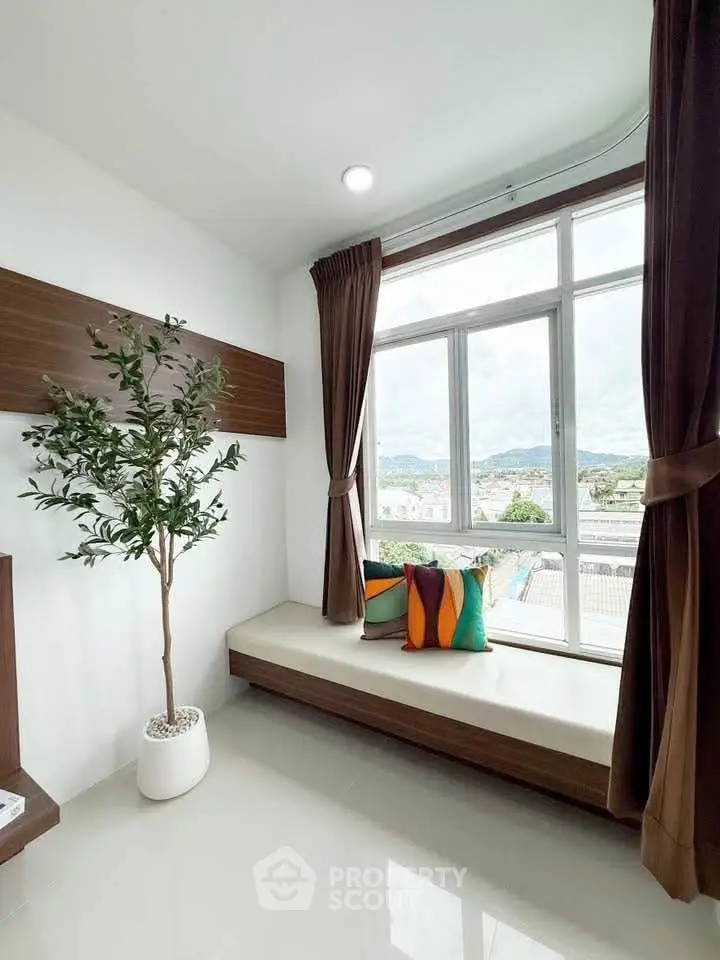 Bright corner unit with large window and scenic view, featuring cozy seating and stylish decor.