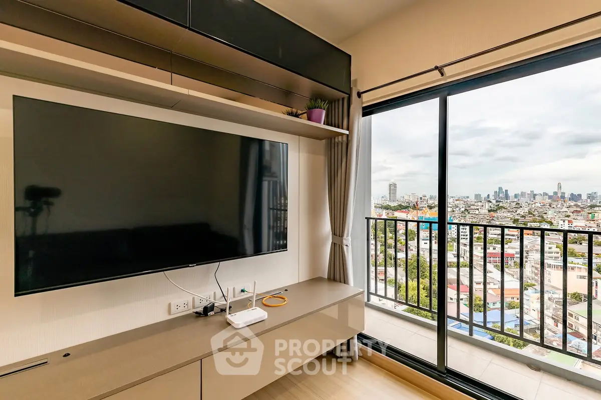 Modern living room with large TV and stunning city view from balcony.