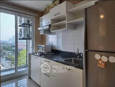 Modern kitchen with sleek cabinets, stainless steel fridge, and city view from window.