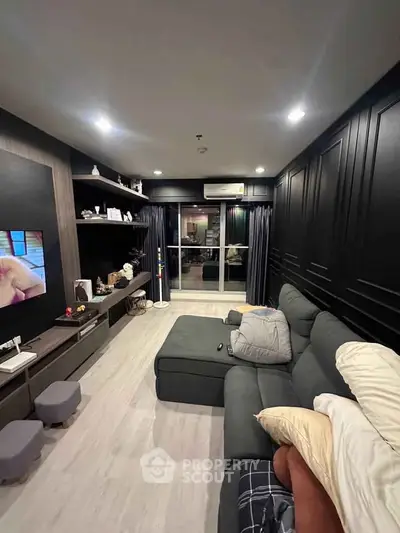 Modern living room with sleek black walls, cozy sectional sofa, and entertainment center.