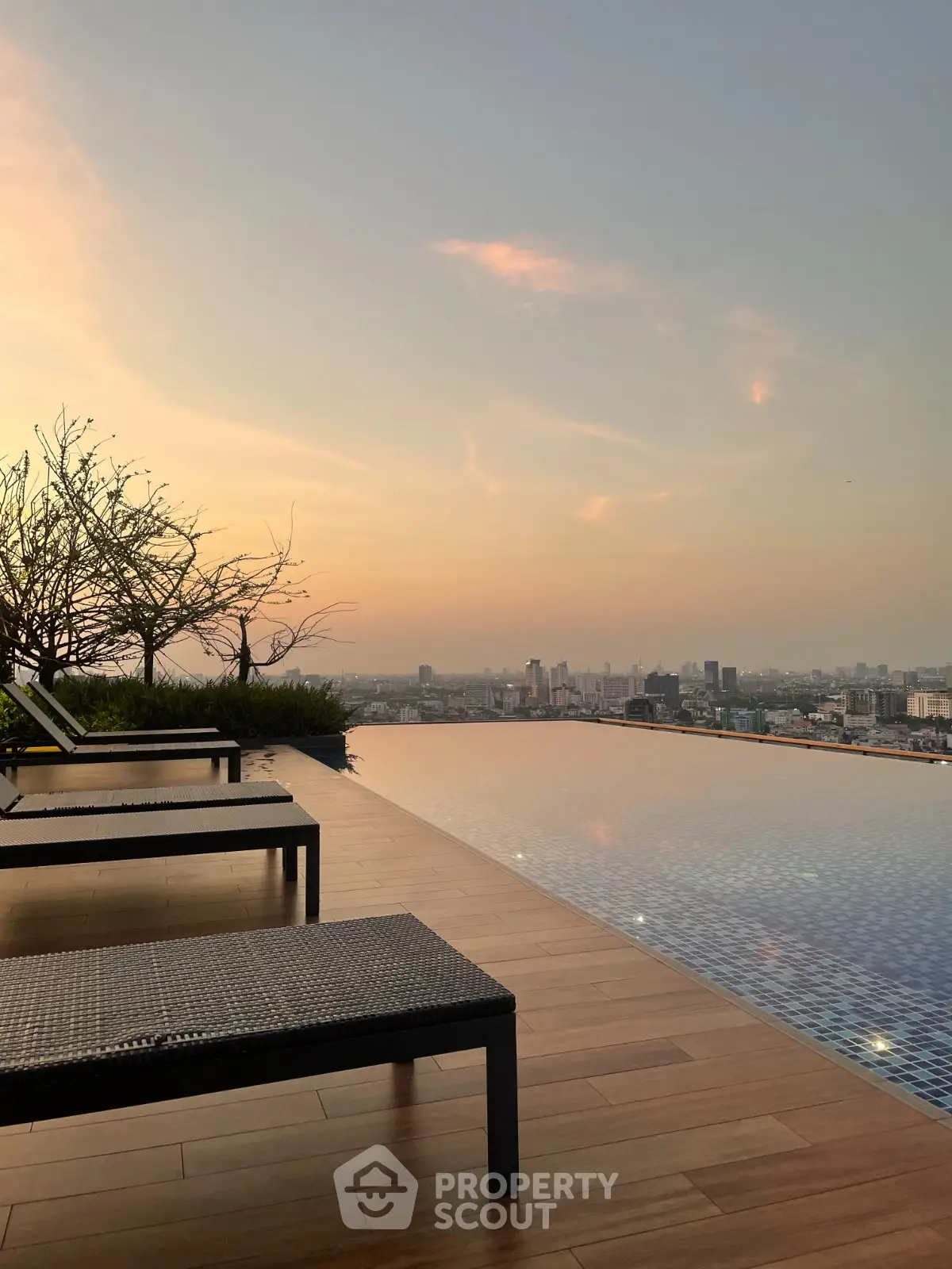 Luxurious rooftop infinity pool with stunning city skyline view at sunset.