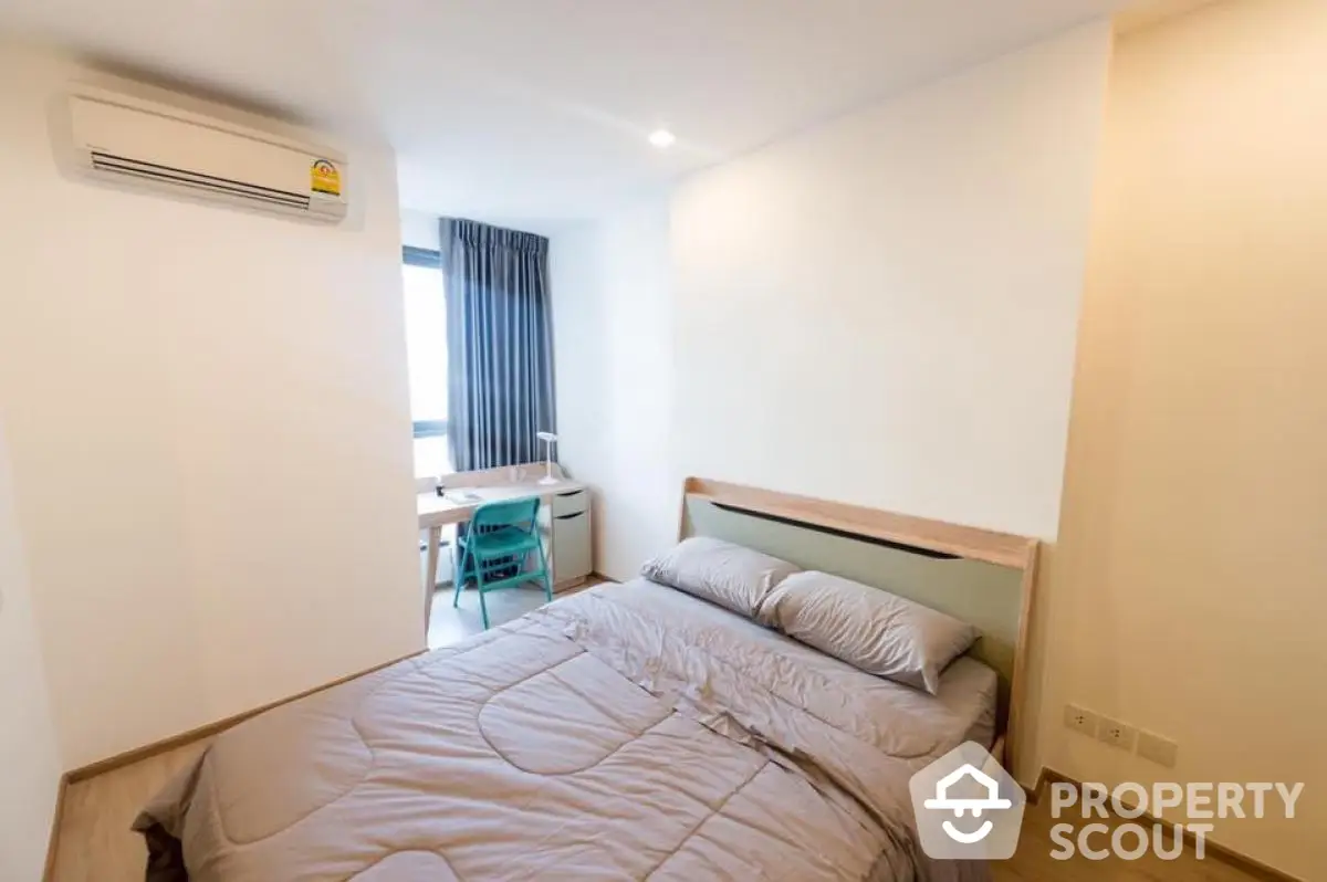 Modern bedroom with cozy bed and study area, featuring natural light and minimalist design.