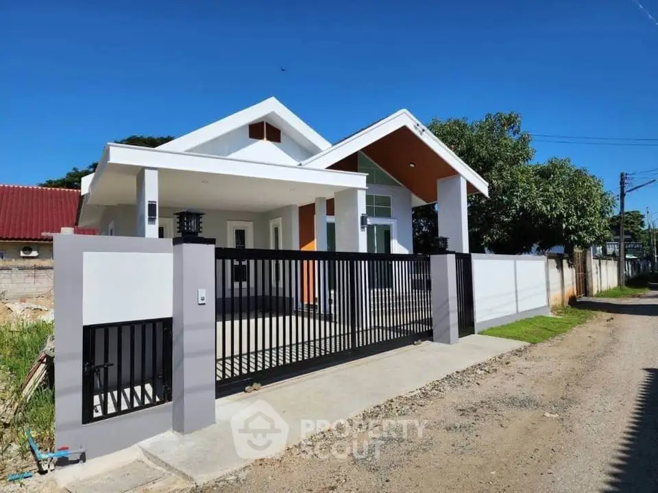 Modern single-story house with gated entrance and spacious driveway in a serene neighborhood.