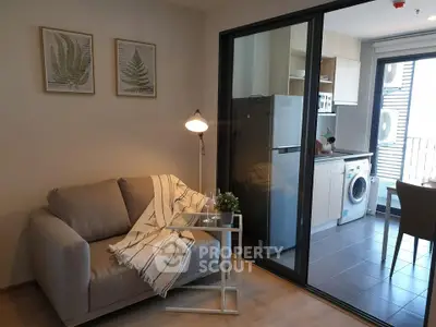 Modern living room with cozy sofa and open kitchen featuring appliances in a stylish apartment.