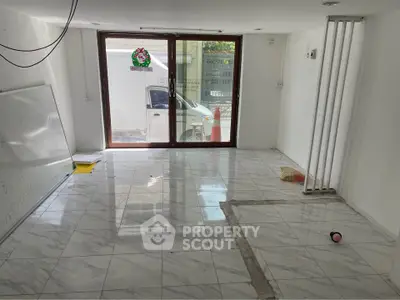 Spacious room with marble flooring and large glass doors leading to outdoor area.