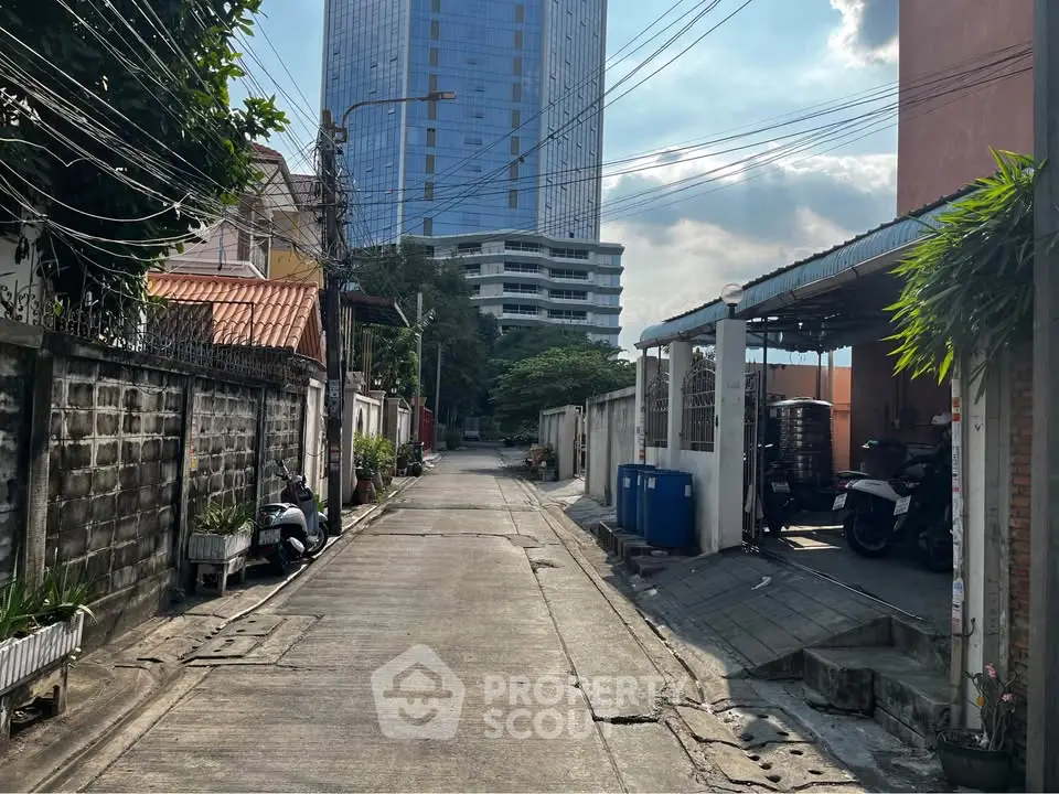 Urban alleyway with residential buildings and high-rise in the background, showcasing city living contrast.