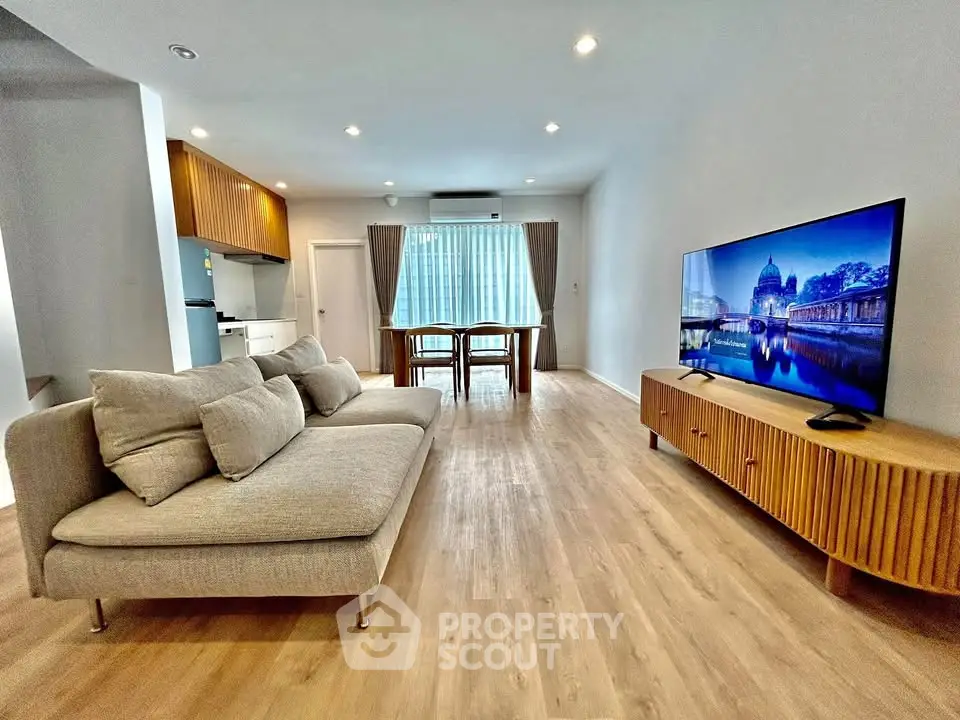 Spacious modern living room with stylish furniture and large TV, perfect for relaxation.