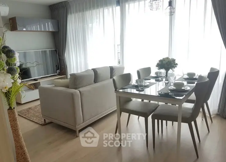 Modern living room with dining area, featuring elegant furniture and large windows for natural light.