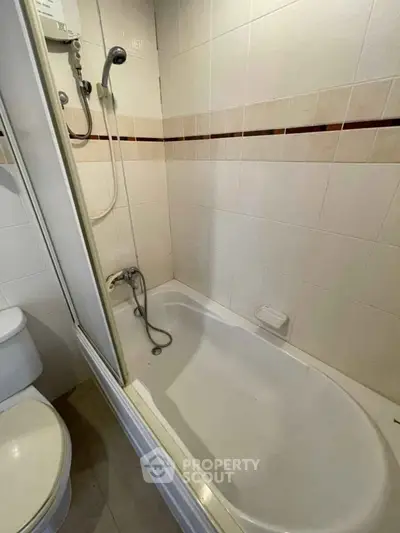 Compact bathroom with bathtub and shower in modern apartment