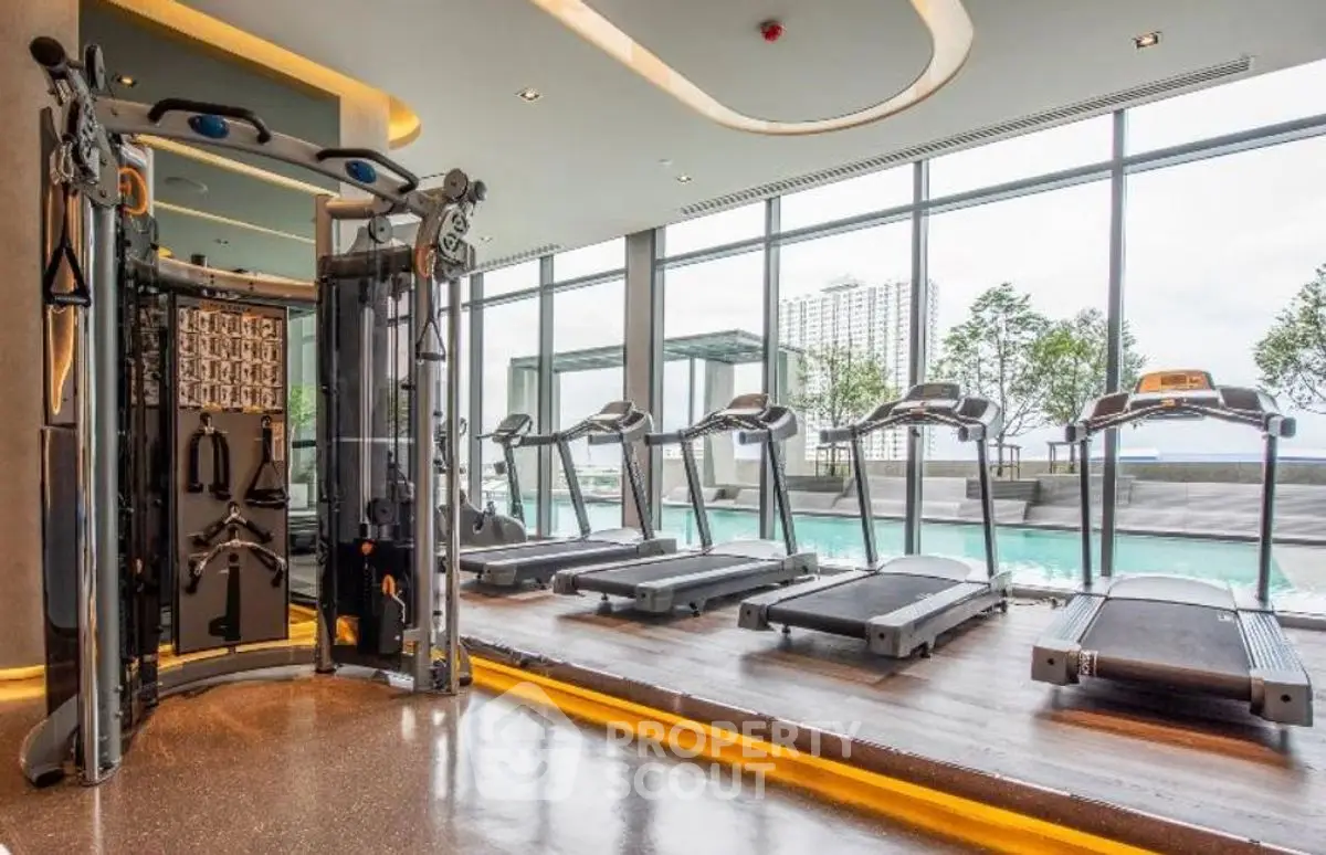 Luxury gym with modern equipment and pool view in upscale apartment complex