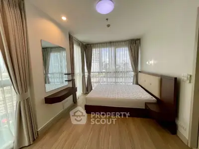 Spacious bedroom with large windows and modern furnishings in a high-rise apartment.