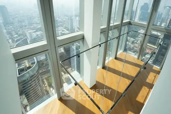 Stunning high-rise apartment with floor-to-ceiling windows offering panoramic city views and sleek wooden flooring.