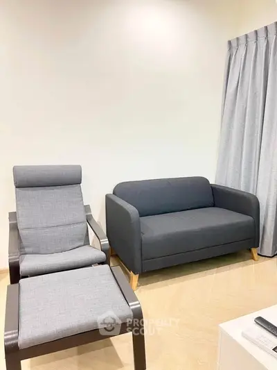 Modern living room with stylish gray sofa and matching armchair, perfect for cozy relaxation.