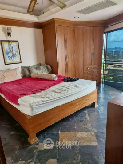 Spacious bedroom with wooden furniture and large windows offering scenic views.