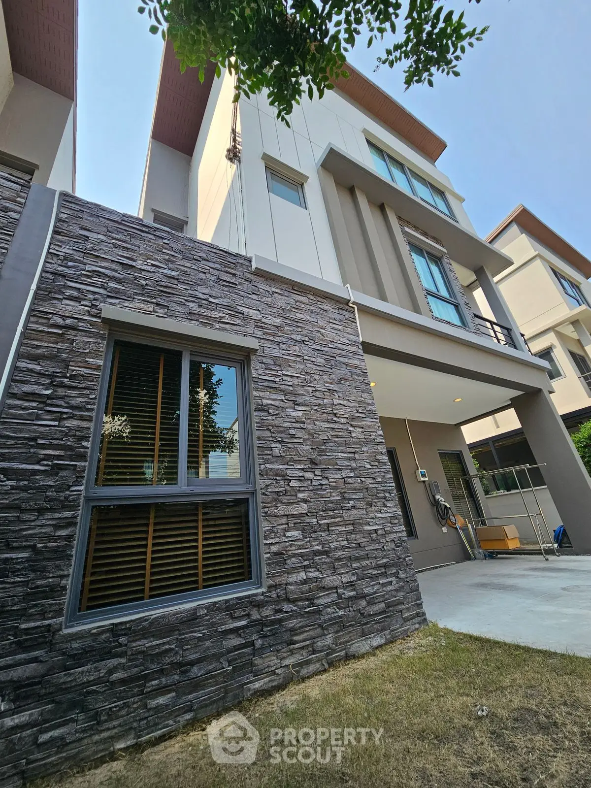 Modern multi-story house with stone facade and spacious balcony in a serene neighborhood.