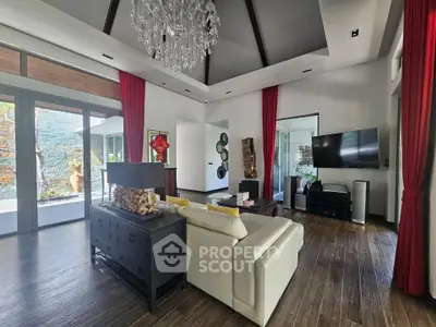 Luxurious living room with chandelier, modern decor, and large windows offering natural light.