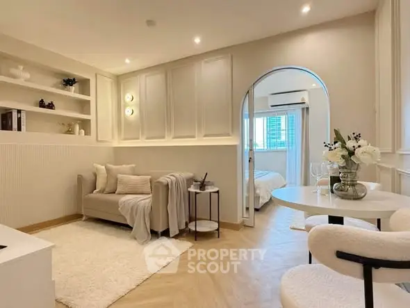 Chic modern living room with cozy seating and elegant decor, leading to a stylish bedroom.