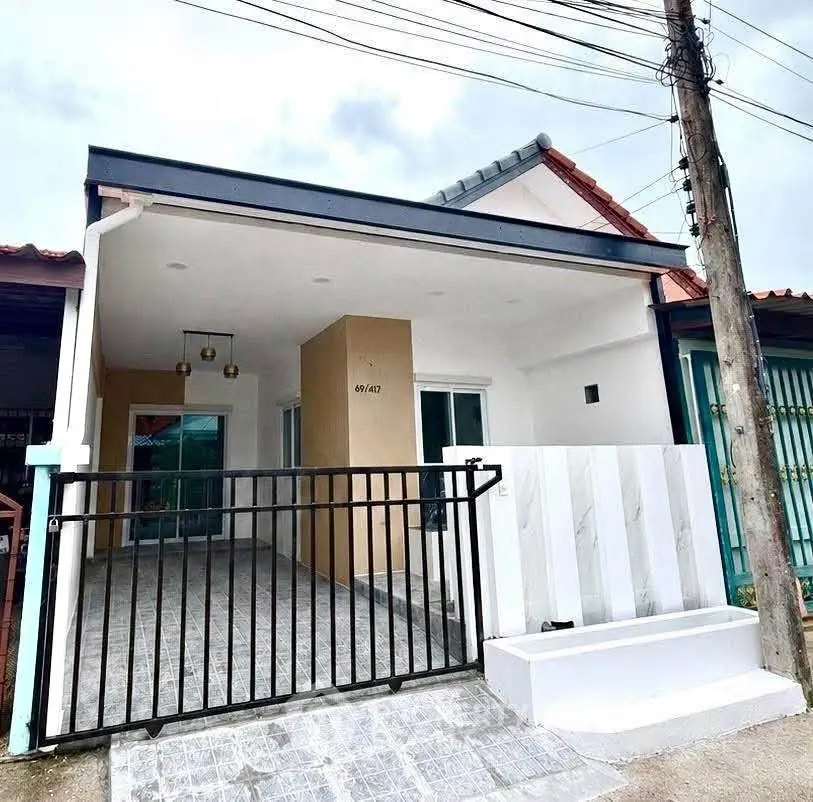 Charming single-story home with modern facade and gated entrance, perfect for cozy living.
