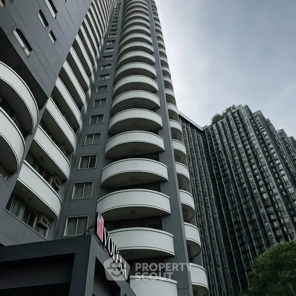 Modern high-rise residential building with curved balconies and sleek design.