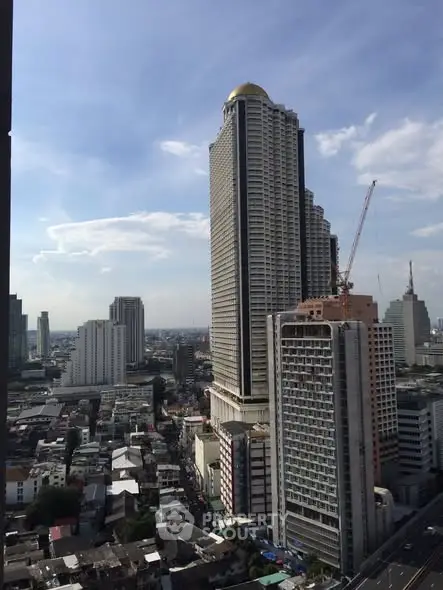 Stunning cityscape view featuring a modern high-rise building with a golden dome under a clear blue sky.