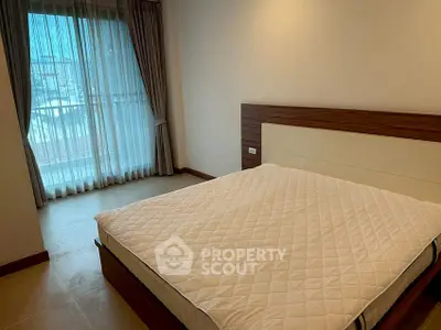 Spacious bedroom with large window and modern furnishings in a stylish apartment.