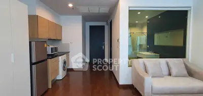 Modern apartment interior with kitchen and living area featuring wooden flooring and sleek design.
