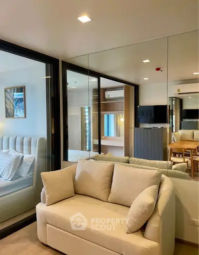 Modern living room with beige sofa and mirrored wall, showcasing elegant interior design.