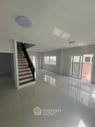 Spacious modern living room with staircase and large windows for natural light.