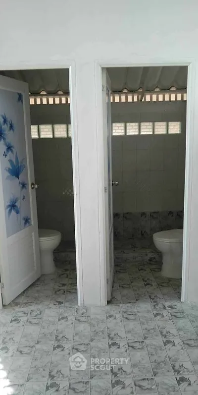 Dual bathroom stalls with tiled flooring and floral door design