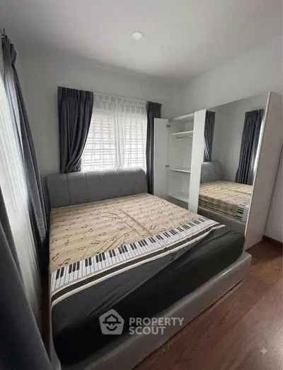 Cozy bedroom with stylish bed and large mirrored wardrobe, perfect for modern living.