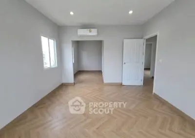 Spacious empty room with wooden flooring and air conditioning, perfect for customization.