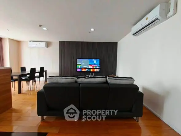 Spacious modern living room with sleek furniture and wall-mounted TV, perfect for relaxation and entertainment.